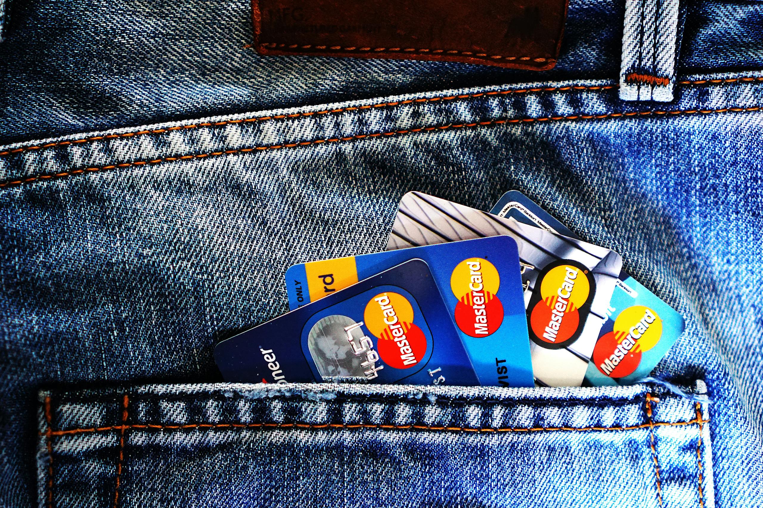 Five credit cards peeking out of Denim Pocket. Just the mastercard logo can be seen on each card.