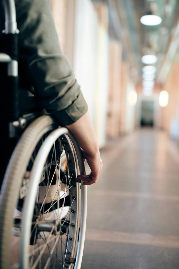 Person Sitting on Wheelchair facing long internal hallway