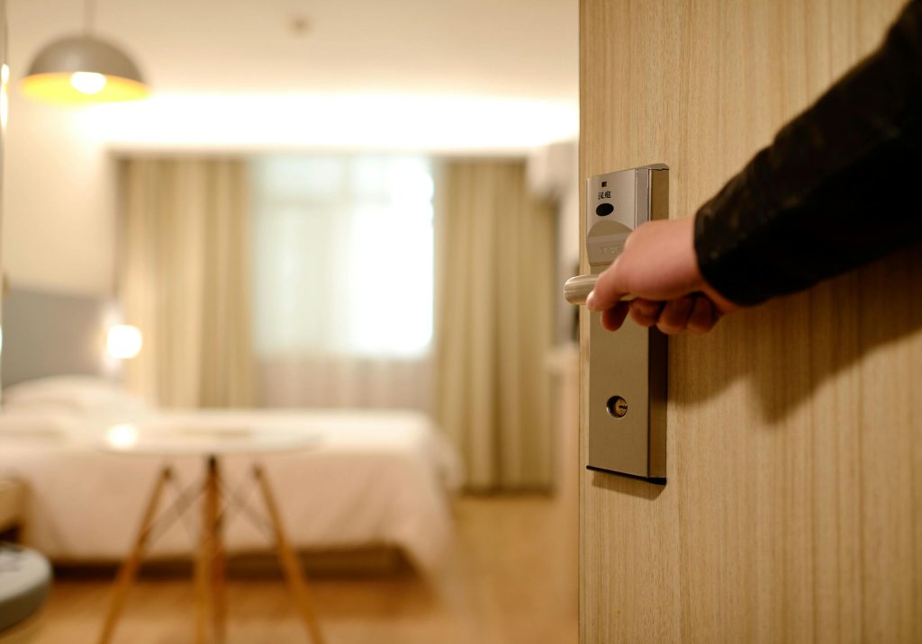 Person Holding on Door handle looking into hotel Room